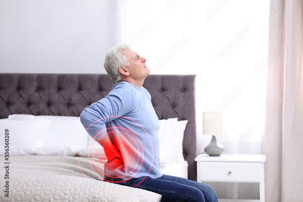 Senior man suffering from back pain after sleeping on uncomfortable mattress at home